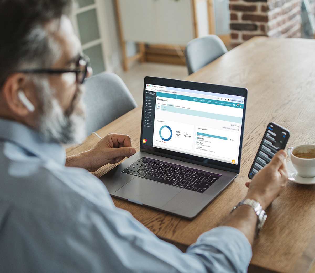 Man sitting at table working on NetCloud Manager on a laptop.
