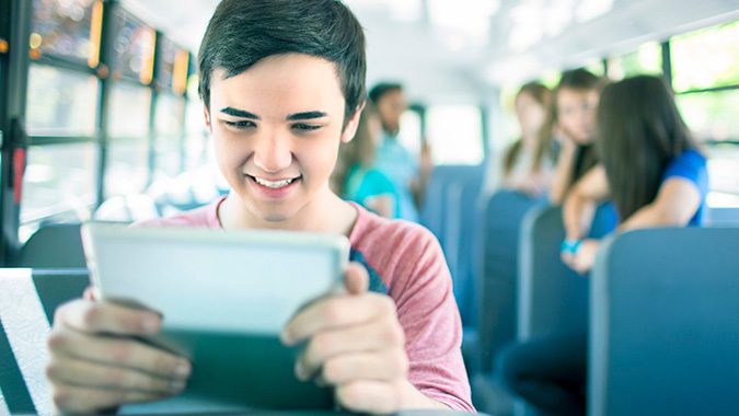 Child sitting on bus using a digital tablet. 