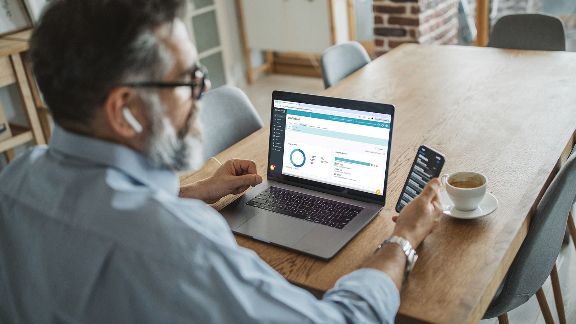 Man sitting at table working on NetCloud Manager on a laptop.